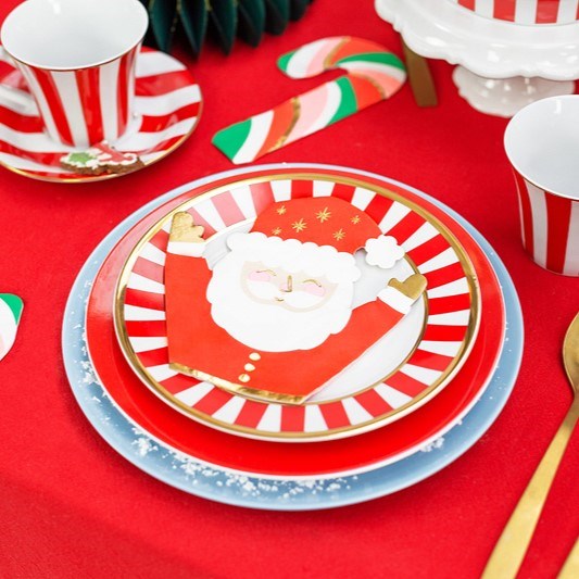 Holiday dinnerware set with striped plates, poinsettia napkins, and Christmas cups