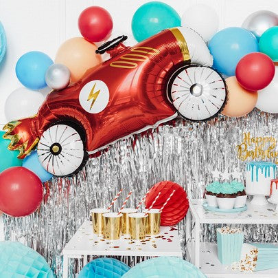 Party Decor Red Car Foil Balloon hanging on a wall with silver curtain  and colorful latex balloons 