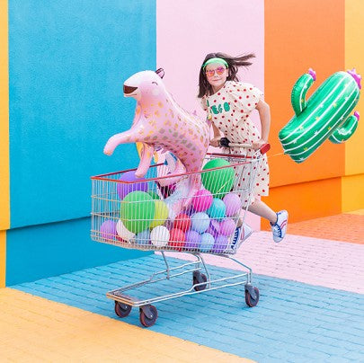 Party Decor Two girls holidy cactus foil balloon, daisy flower foil balloon and a pink leopard foil balloon in front of a colorful wall
